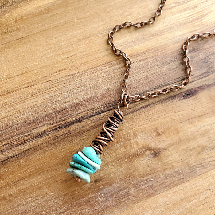 Turquoise chips copper wrap pendant on wood