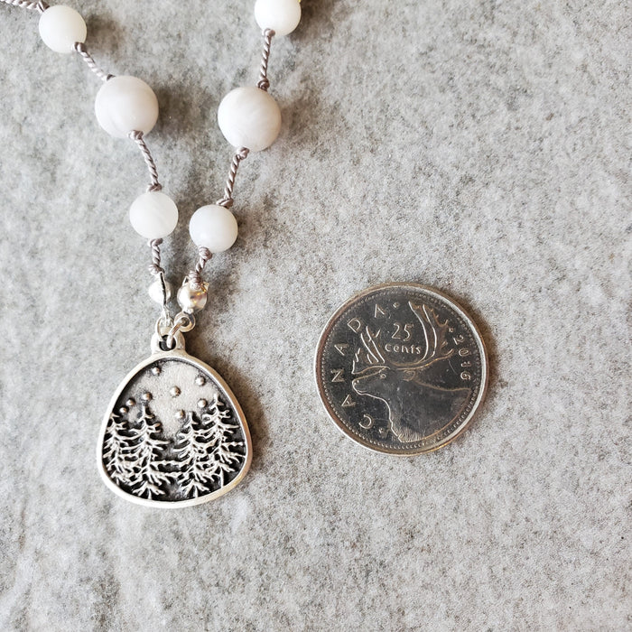 White crazy lace agate knotted necklace beside a quarter