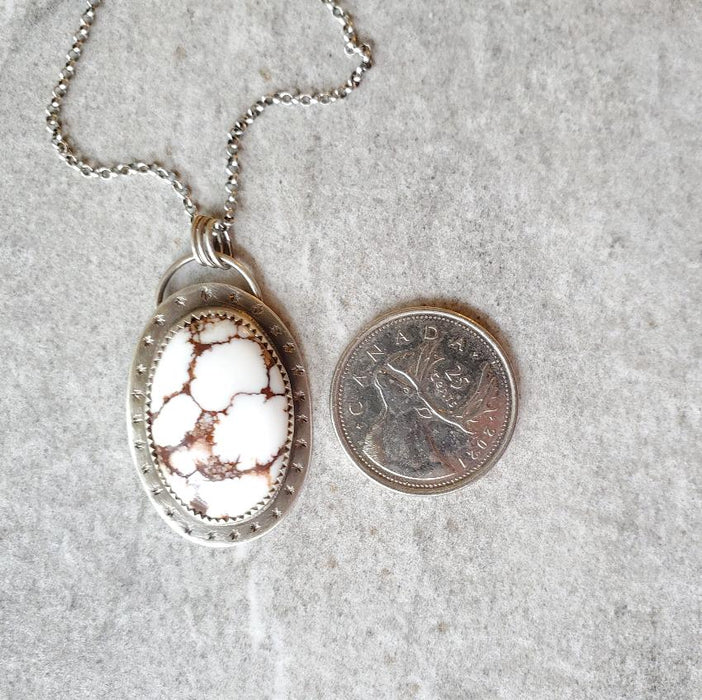 Wild Horse Magnesite silversmith pendant beside a quarter