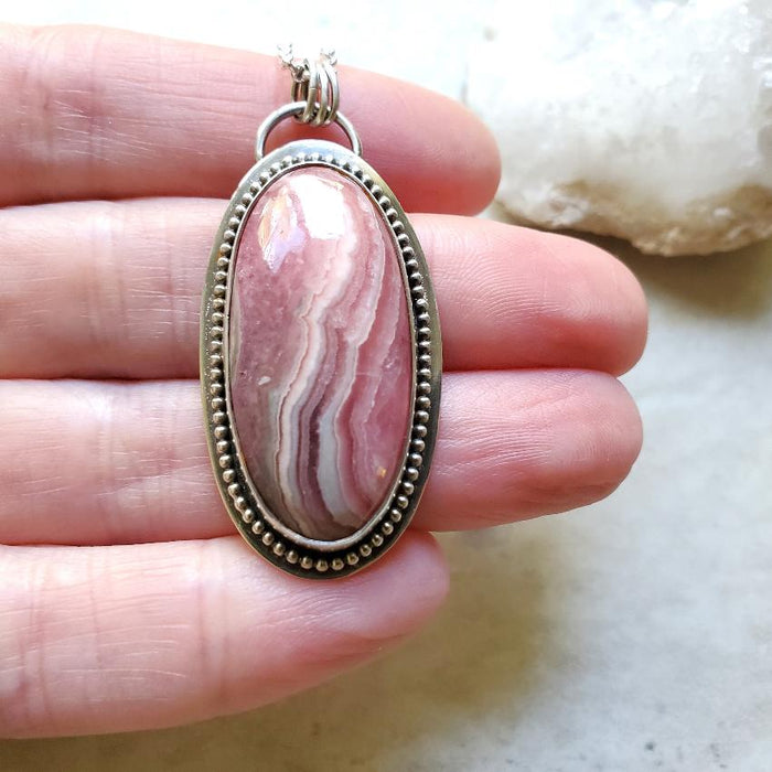 Rhodochrosite oval silversmith pendant necklace in hand