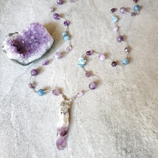 Necklace with amethyst pendant on a textured surface