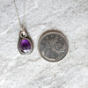 Faceted Amethyst silversmith necklace beside a quarter