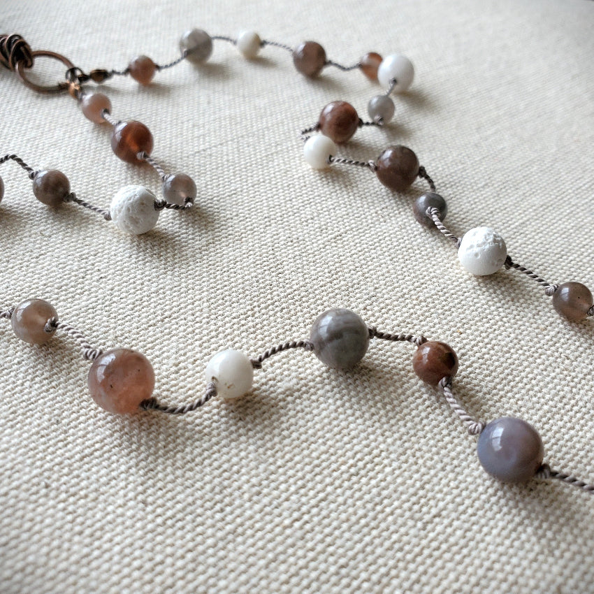 Necklace with multicolored beads on a textured fabric background