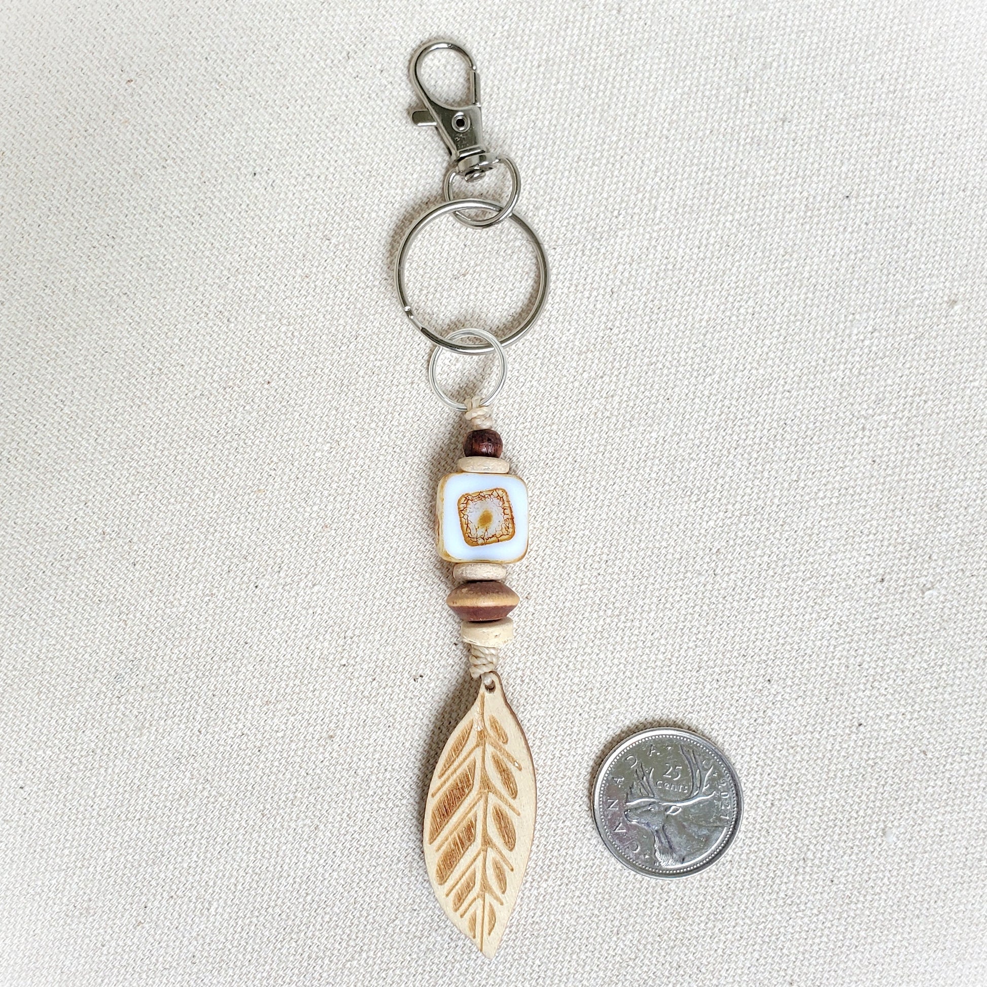Keychain with feather charm and bead on a light gray background