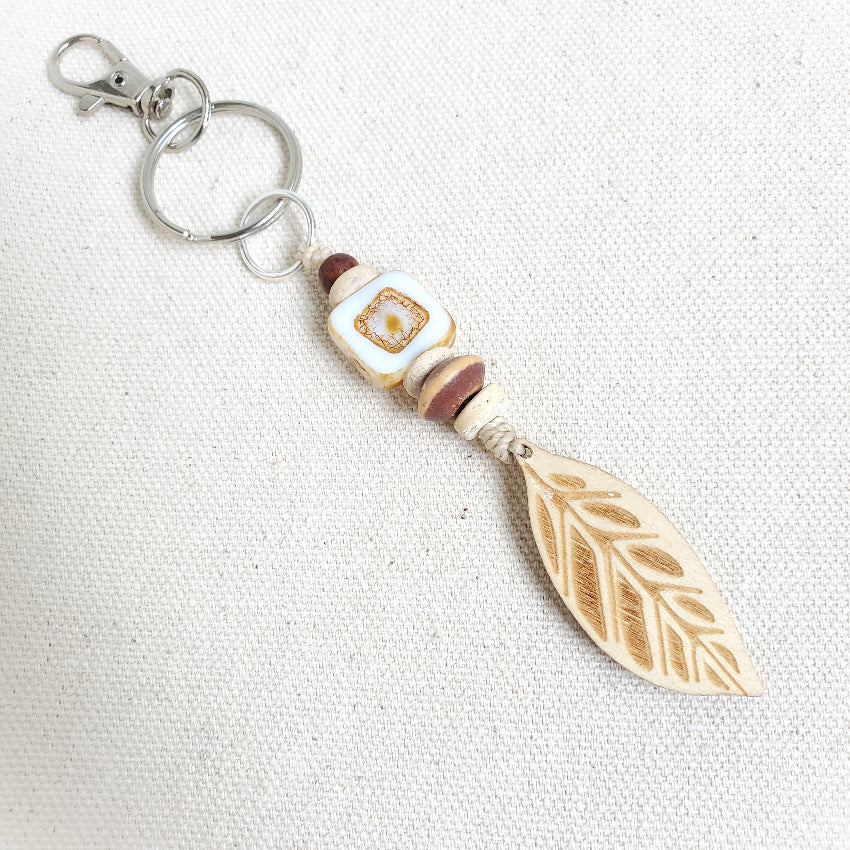 Keychain with leaf design and decorative bead on a white background