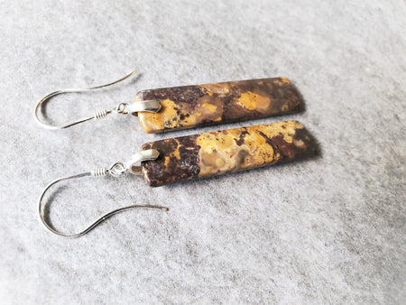 natural Bird's Eye Rhyolite stones feature warm earthy tones of mustard yellow and rich brown. The stones hang on genuine sterling silver bails and ear wires. 