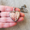 Alunite heart gemstone pendant in hand