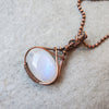 Oval Rainbow Moonstone wire wrapped in copper wire and hanging from copper chain