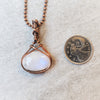 Oval Rainbow Moonstone wire wrapped in copper wire and hanging from copper chain
